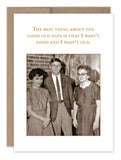 The Good Old Days Birthday Card by Shannon Martin Design features a vintage photograph printed on recycled paper. In the photo, a woman in a dress, a man in a suit, and an elderly woman stand indoors. The text above them humorously proclaims, "The best thing about the good old days is that I wasn‚Äôt good and I wasn‚Äôt old." Crafted with classic charm in the USA.