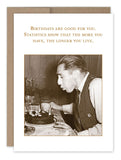 In a series of vintage photos, a man blows out candles on his birthday cake. The caption above humorously notes, "Birthdays are good for you. Statistics show that the more you have, the longer you live." - featured in the Shannon Martin Design's Longer You Live Birthday Card.