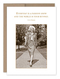 A Shannon Martin Design Fashion Show Birthday Card features a vintage-style image of a woman in a tailored suit and hat, confidently walking on a pathway. The card, printed on recycled paper, reads: "Everyday is a fashion show and the world is your runway." - Coco Chanel.