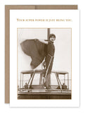 The "Your Super Power Birthday Card" by Shannon Martin Design showcases a Shero standing proudly on a boat, her coat flowing like a cape. Made from recycled paper, it features the text, "Your super power is just being you.