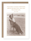 A sepia-toned image from Shannon Martin Design's My Life Birthday Card features a woman lounging on a wicker chair at the beach, evoking the feel of vintage photos. She smiles with her arms behind her head, while the top text reads, "I am going to make everything around me beautiful and that will be my life." - Elsie de Wolfe.