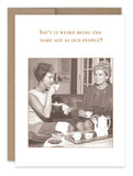 Two women from a bygone era sit on a couch, sipping tea and dressed with elegance. Above them, the humorous text reads, "Isn‚Äôt it weird being the same age as old people?" This charming vintage scene is perfectly captured in the "Same Age Birthday Card" by Shannon Martin Design, crafted on recycled paper cards made in the USA.