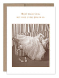 A sepia-toned, vintage-inspired birthday card by Shannon Martin Design features a woman in a frilly dress lounging on a striped sofa with shoes on the floor. The text above humorously states: Born to Be Wild Birthday Card printed on FSC-certified, recycled paper for sustainable nostalgia preservation.