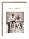 The Happiness Anniversary Card by Shannon Martin Design showcases a vintage photo of a smiling couple sitting in a rowboat and holding hands. The card is elegantly framed with a beige border on recycled paper and includes the quote by George Sand, "There is only one happiness in life, to love and be loved.