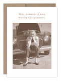 The Rock Bottom What A Hoot Card by Shannon Martin Design features a sepia-toned image of a woman sitting thoughtfully on a curb with an open-hood vintage car in the background. The text above her humorously states, "Well, apparently rock bottom has a basement," evoking the charm of vintage photos printed on recycled paper.