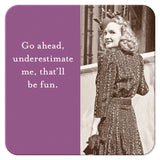 This vintage black-and-white photo features a woman in a textured dress and hat, smiling over her shoulder. The left side of the image is designed with a purple background and white text that reads, "Go ahead, underestimate me, that‚Äôll be fun." The Go Ahead Coaster by Shannon Martin Design makes an ideal hostess gift when paired with cork-based coasters.