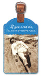 The Shannon Martin Design Happy Place Luggage Tag beautifully features a vintage photo of a person in white attire relaxing on rocks at the seashore. This blue leatherette tag, equipped with a copper metallic strap, is inscribed with the phrase: If you need me, I'll be in my happy place.