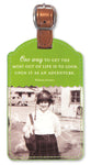 The Most Luggage Tag by Shannon Martin Design is a leatherette tag in green, showcasing a vintage photo of a smiling person wearing a helmet and holding a bag. It features a copper metallic strap and the quote: "One way to get the most out of life is to look upon it as an adventure." - William Feather.