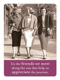 Three women strolling side by side on a street, dressed in mid-20th century fashion and accessorized with playful details. They're smiling and involved in a vibrant conversation. Below them: "Friends We Meet Magnet" by Shannon Martin Design ‚Äì reminding us that the friends we meet along the way act as magnets, enhancing our appreciation of life‚Äôs journey.